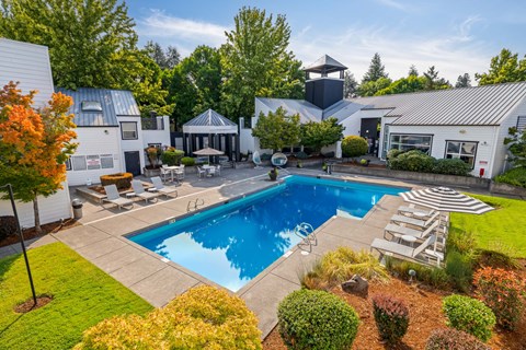 Pool and spa with view of clubhouse and trees in background.