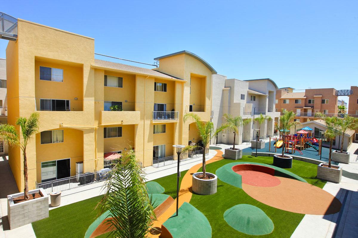 A playground area with a slide and a green lawn in front of apartment buildings.