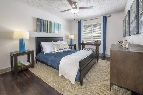 A bedroom with a bed, nightstand, and a ceiling fan.