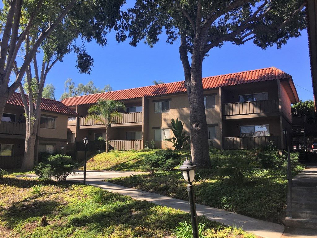 a row of apartment buildings with sidewalks and trees in front of them
