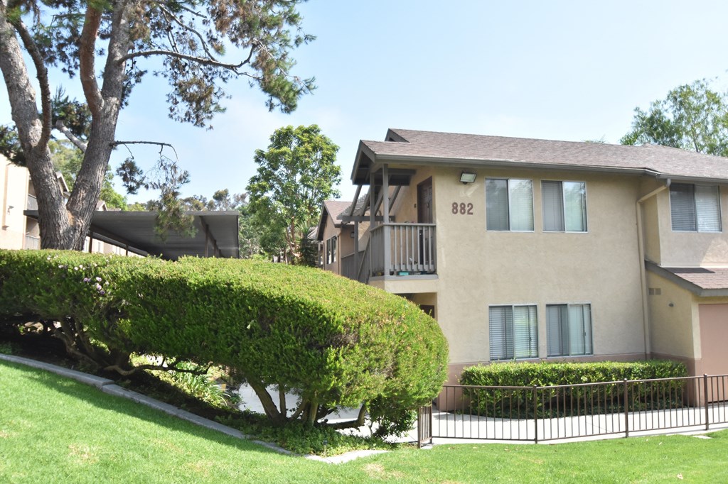 a large apartment building with a lawn and trees in front of it