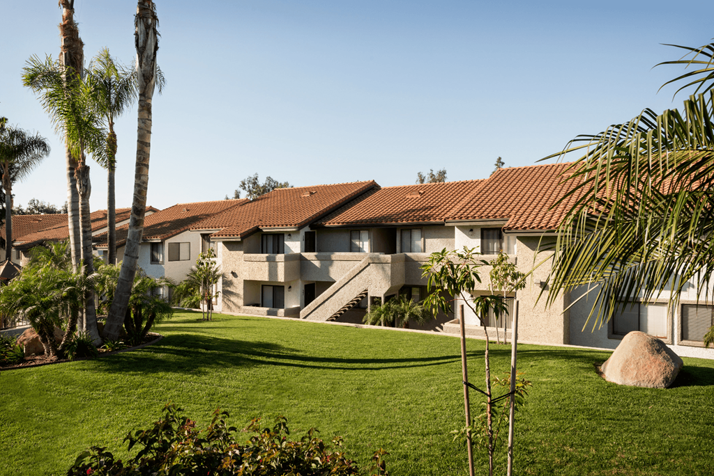 a row of apartment buildings with palm trees in the foreground