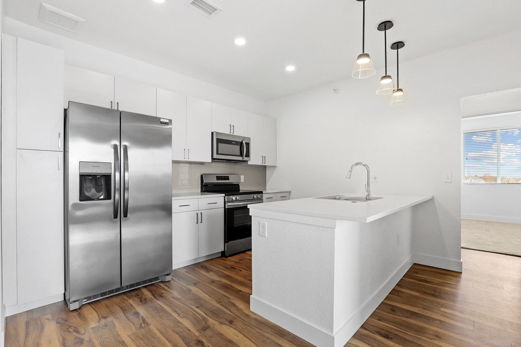 a white kitchen with stainless steel appliances and a white counter top