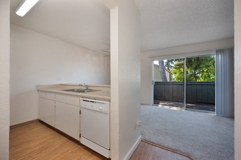 an empty kitchen and living room with a sliding glass door to a patio