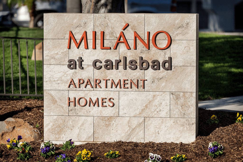 a large stone sign that reads milano at carlsbad apartment homes