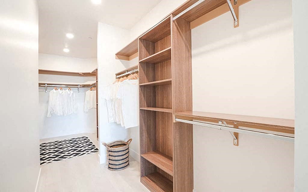 a walk in closet with wooden shelves and white walls