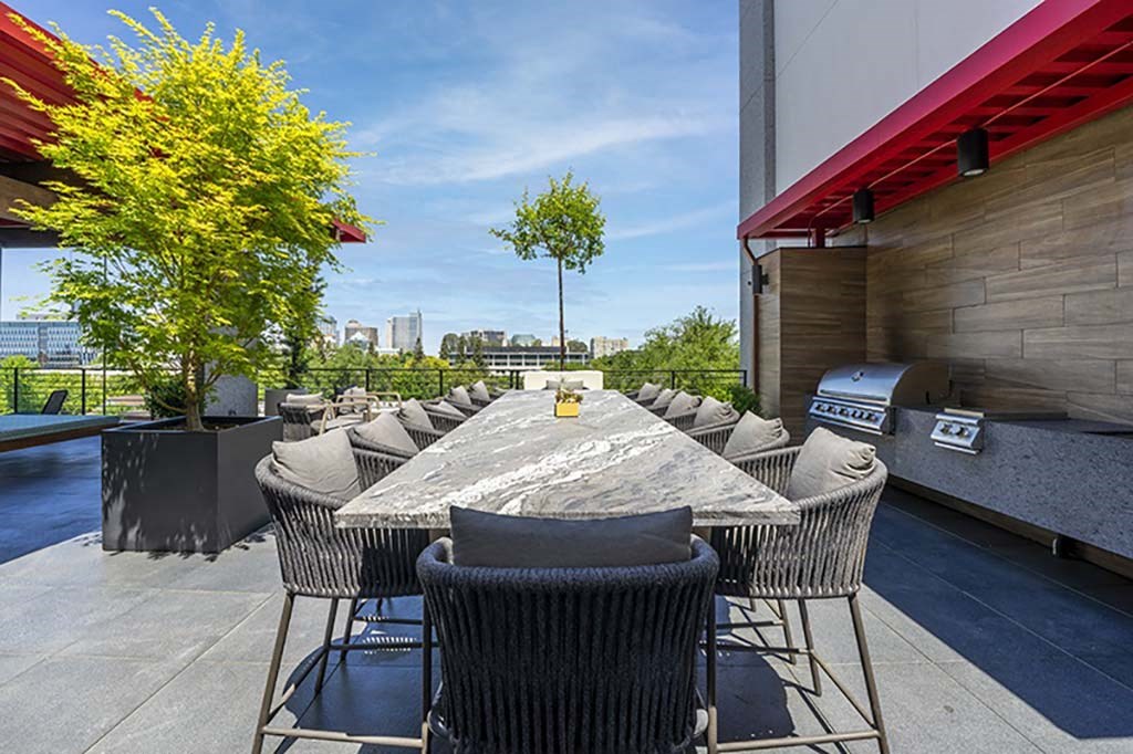 a patio with a table and chairs and a grill