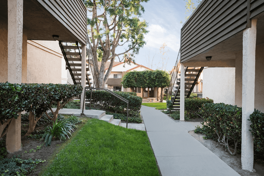 a walkway between two buildings with a tree in the background