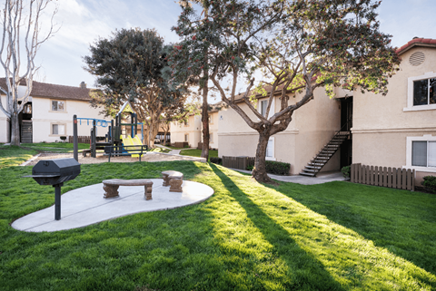 The courtyard area with a barbecue, two benches, and the park in the background.