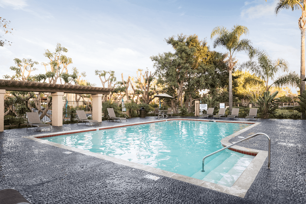 a swimming pool with chaise lounge chairs and trees in the background