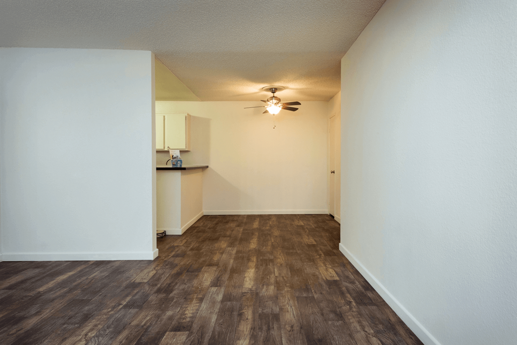 a living room with white walls and a ceiling fan
