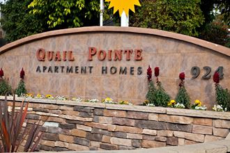 a stone wall with a sign that reads quail pointe apartment homes