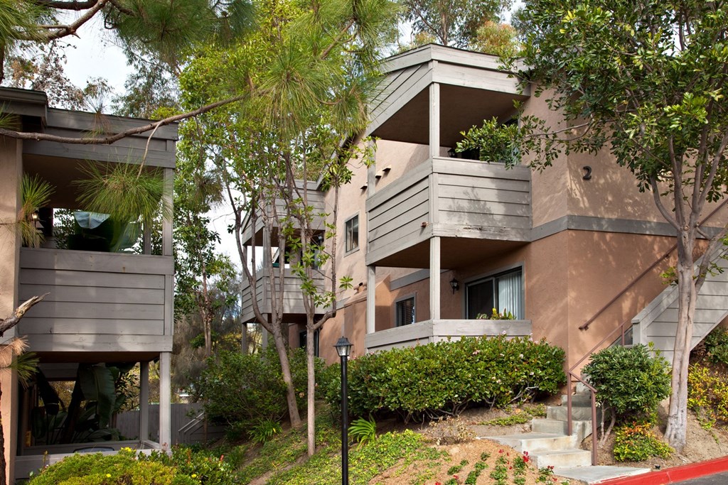 an apartment building on a hillside with trees in front of it