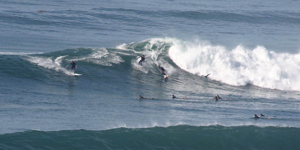 a group of surfers riding a wave in the ocean