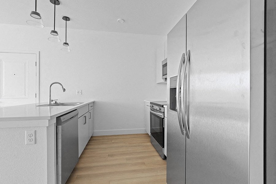an empty kitchen with stainless steel appliances and white counter tops