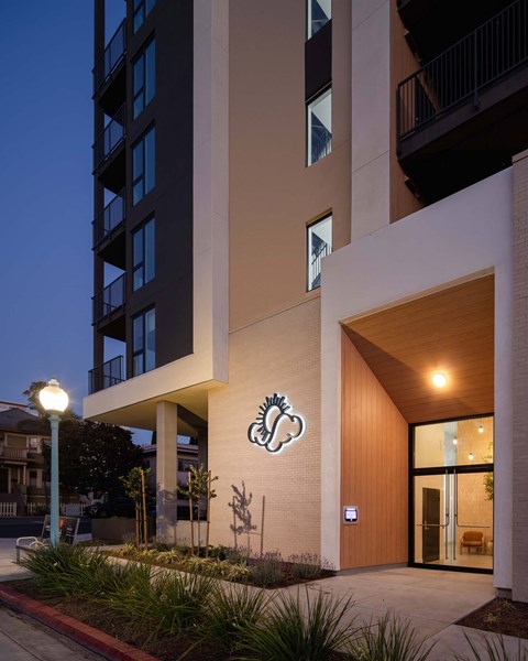 A modern building with a wooden entrance and a sign with a stylized flower.