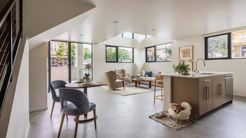 A modern kitchen and dining area with a dog on the rug.