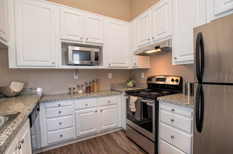 A kitchen with white cabinets and a black refrigerator.