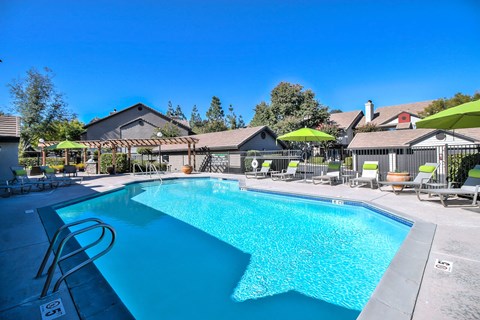 A large swimming pool surrounded by lounge chairs and umbrellas.