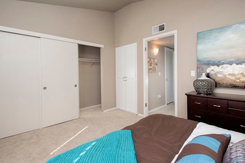 A bedroom with a bed, a wardrobe, and a painting on the wall.