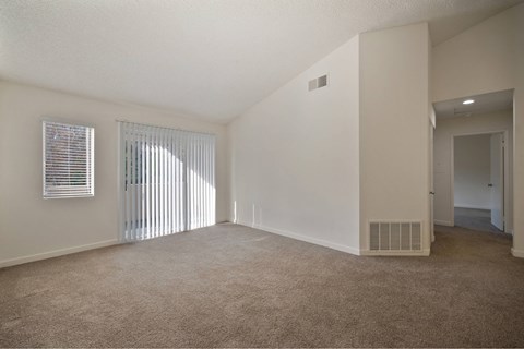 A sparsely furnished room with a window covered by blinds.