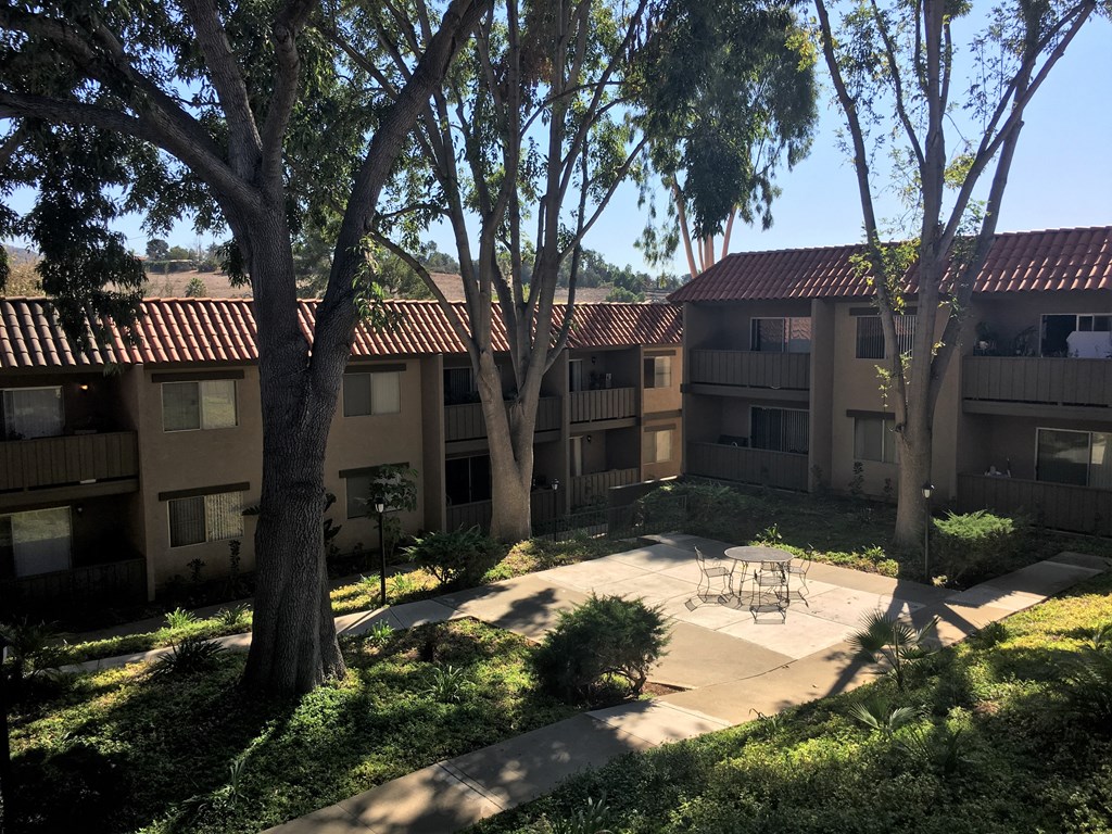 a courtyard with trees and a firepit at the whispering winds apartments in pearland, tx