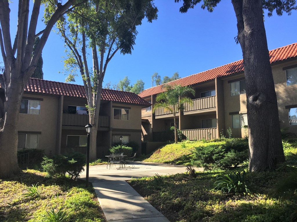 a courtyard with trees and a table and chairs in the middle of the courtyard