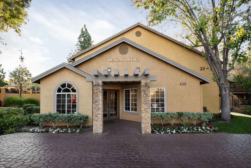 a brick building with awning and trees in the background