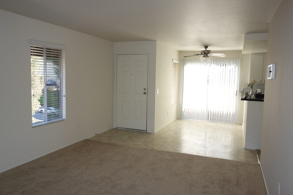 an empty living room with a window and a ceiling fan