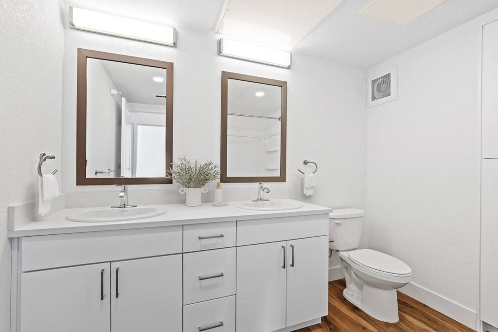 a white bathroom with two mirrors and a toilet