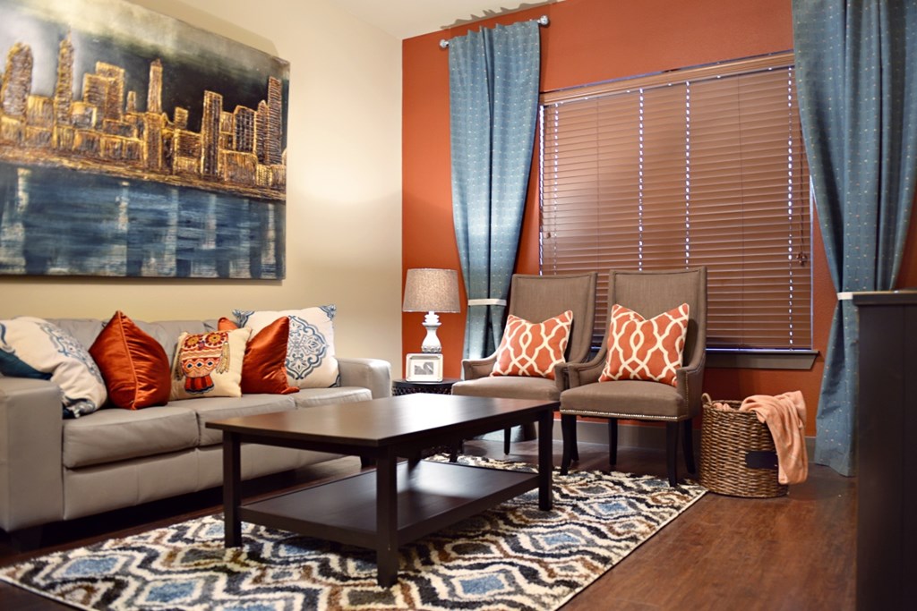 A living room with a grey couch, a coffee table, and a cityscape painting on the wall.