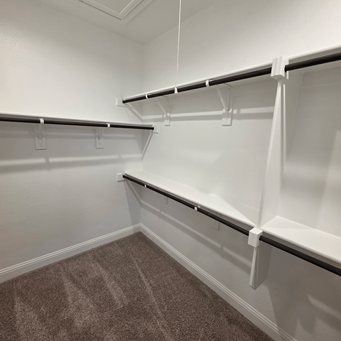 Empty white shelves in a room with carpeted floor.
