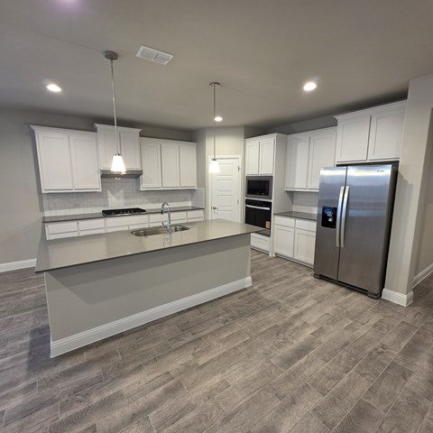A modern kitchen with white cabinets and a wooden floor.