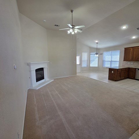 A living room with a fireplace and a ceiling fan.