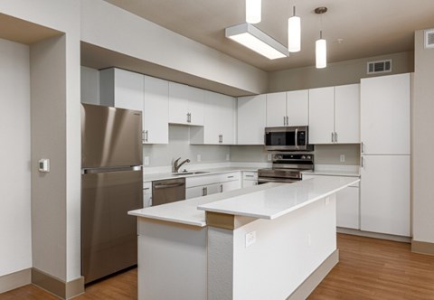 A modern kitchen with white cabinets and a stainless steel refrigerator.