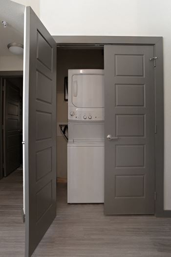 an open door to a kitchen with a refrigerator and a washing machine at The Liberty Lofts, Gainesville, TX