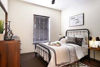 a bedroom with a bed and a dresser and a window at The Liberty Lofts, Gainesville, TX, 76240