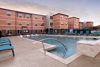 an image of a city with a pool and buildings with orange lights at The Liberty Lofts, Gainesville, 76240