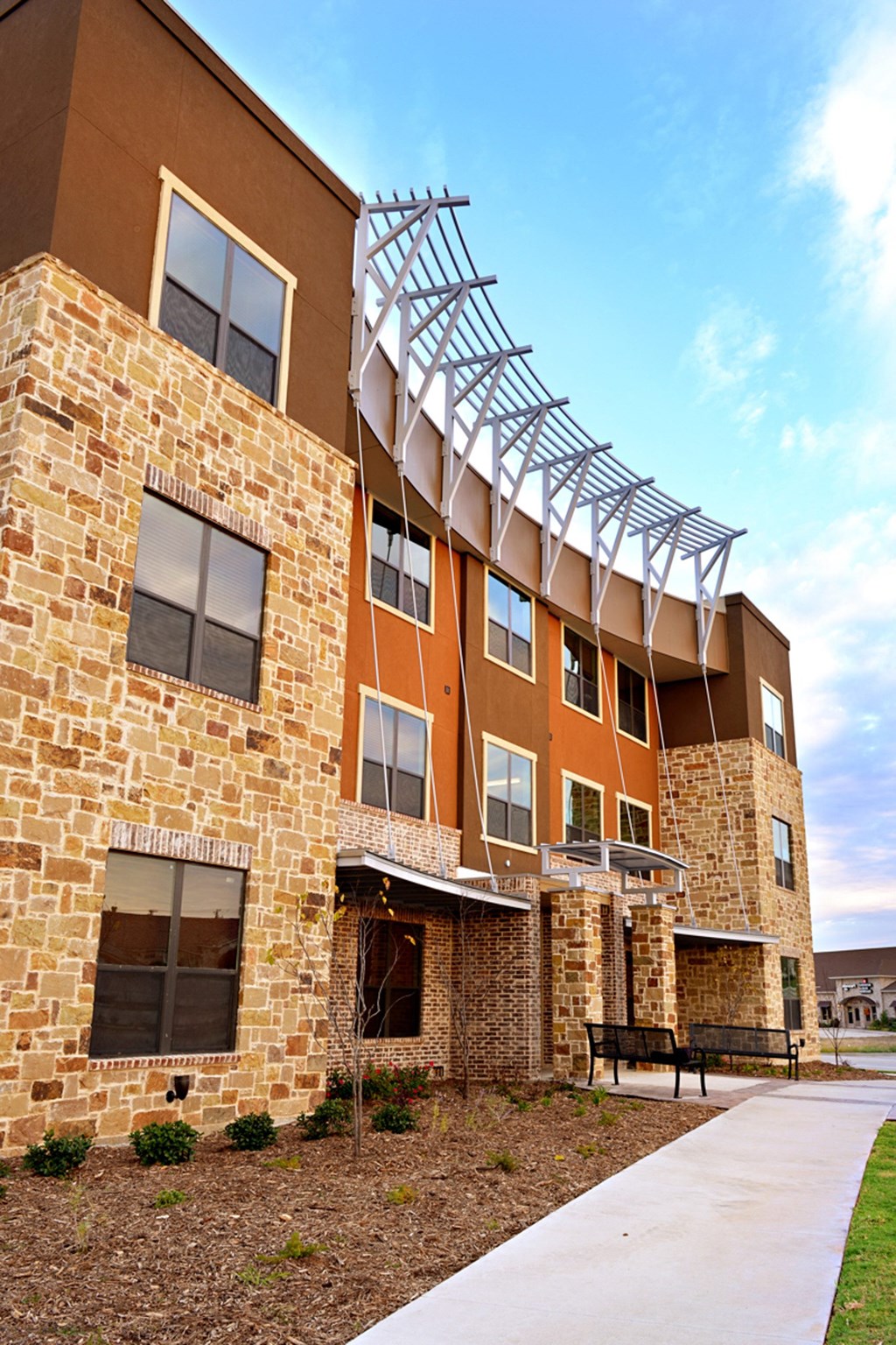 an exterior view of a building with a bench in front of it at Urban Square, Denton, TX