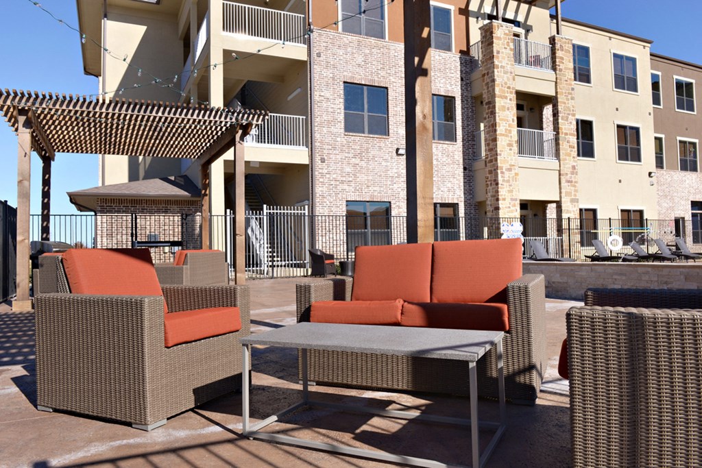 a patio with chairs and a table in front of a building
