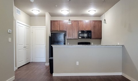 A kitchen with a black refrigerator and brown cabinets.