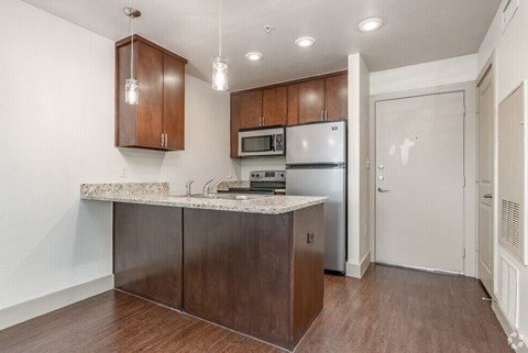 A kitchen with brown cabinets and a marble countertop.