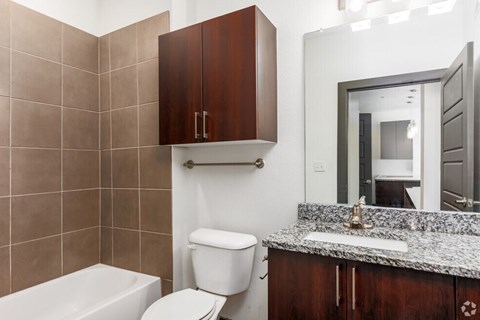 SevenTwelve Lofts Downtown UNT Denton Apartments A bathroom with a toilet, sink, and mirror.
