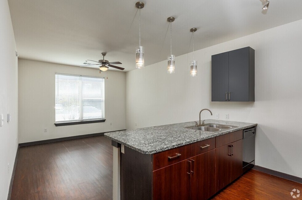 A kitchen with a granite countertop and wooden cabinets.