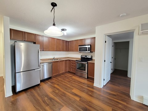 A kitchen with wooden cabinets and a stainless steel refrigerator.