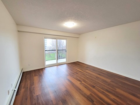an empty living room with hard wood flooring and a window