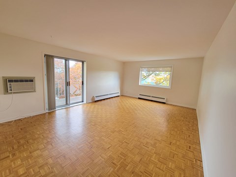 A room with wooden flooring and a window with a view of trees.