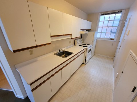 A kitchen with white cabinets and a window.