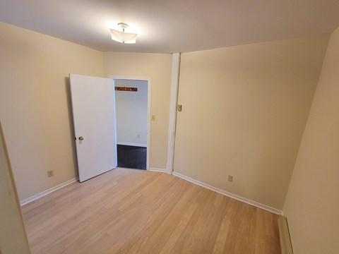 A room with a white door and wooden flooring.
