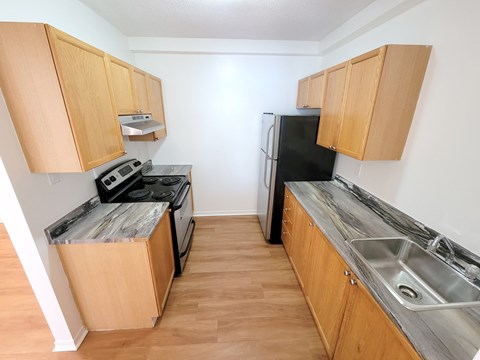 A kitchen with wooden cabinets and a black fridge.